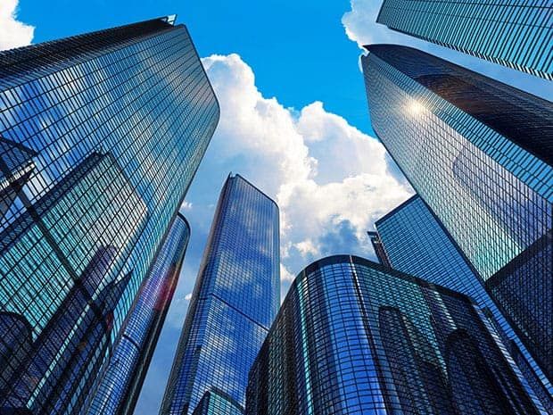 Modern glass skyscrapers reflecting the blue sky and clouds, representing the growth, scale, and opportunities within the commercial real estate market.